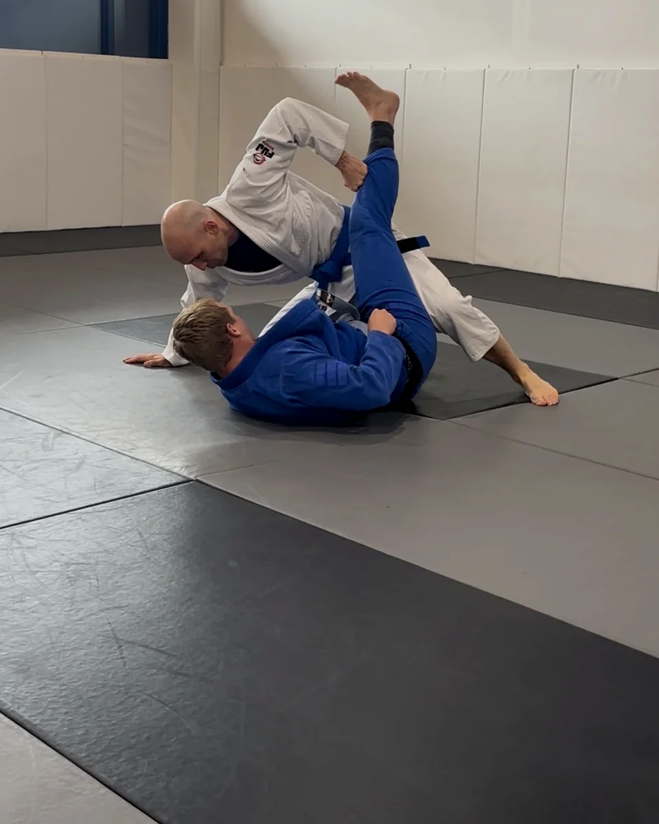 Adults drilling gi Jiu-Jitsu technique on the mats