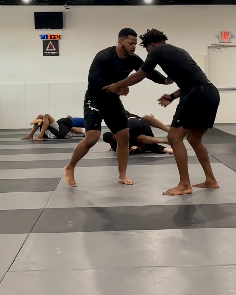 Adults practicing no-gi control on the mat
